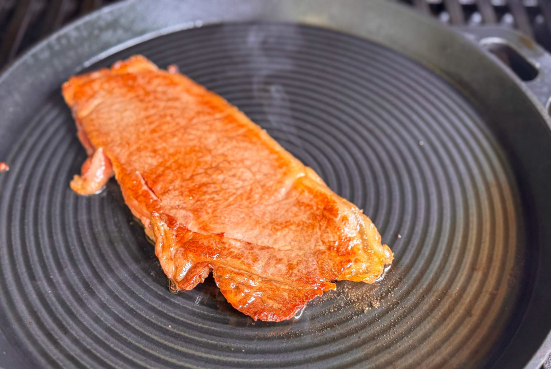 Wagyu A5 Steak wird in einer gerillten Gusseisenpfanne angebraten – intensive Farbe, feine Kruste, hoher Fettgehalt sichtbar.
